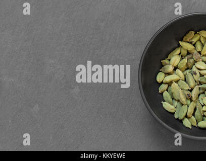 Les graines de cardamome dans un bol sur la table gris Banque D'Images