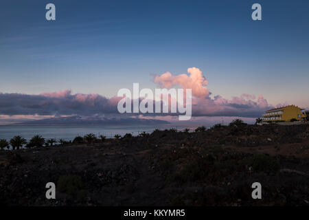 Bloc d'appartement avec vue sur la côte ouest que le soleil levant éclaire les nuages au-dessus de la mer avec l'île de La Gomera à l'horizon, l'aube en pla Banque D'Images