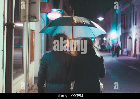 Couple marche à la pluie sur une nuit sombre route avec l'Europe de l'Est pluie Banque D'Images