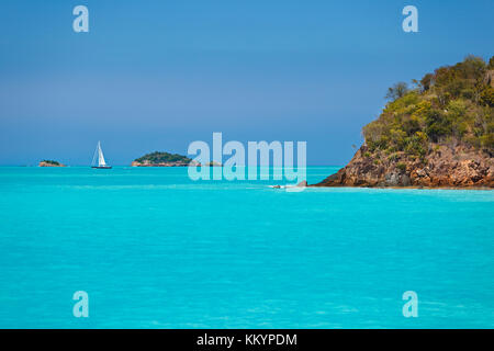 Un petit voilier en croisière entre les îles de la mer turquoise. Banque D'Images