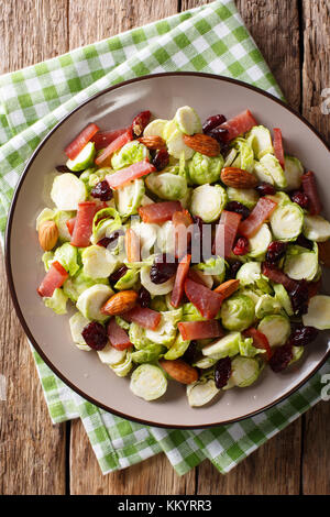 Salade maison de tranches de choux de Bruxelles, les canneberges, les amandes et le jambon sur une assiette sur une table. vertical haut Vue de dessus Banque D'Images