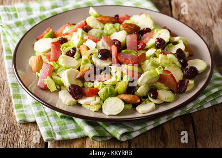 L'alimentation saine : salade de choux de Bruxelles, les canneberges, Amandes et de jambon sur une plaque sur une table horizontale. Banque D'Images