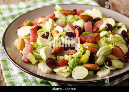 Salade saine de choux de Bruxelles, les canneberges, Amandes et de jambon sur une plaque sur une table horizontale. Banque D'Images