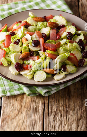 Salade de choux de Bruxelles, des canneberges séchées, des amandes et de jambon sur une plaque sur une table verticale. Banque D'Images