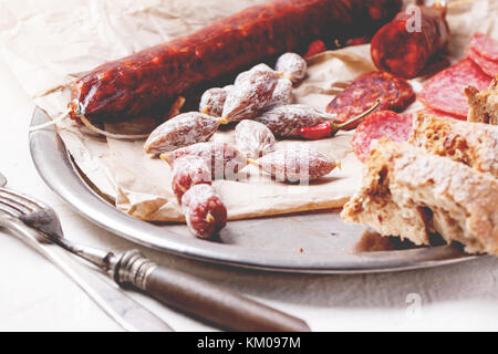 Ensemble de salami saucisses servis avec du pain frais et Red Hot Chili Peppers sur plateau vintage Banque D'Images