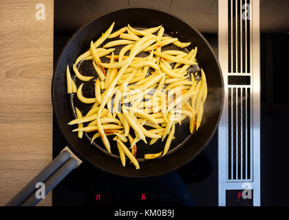 En forme de doigt boulettes de pommes de terre dans une poêle en fonte sur une cuisinière avec hotte aspirante Banque D'Images