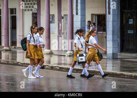 Quatre filles d'école se font une pause déjeuner et se demandent les rues de Moron, la capitale du district de Ciego de Avila à Cuba. Banque D'Images