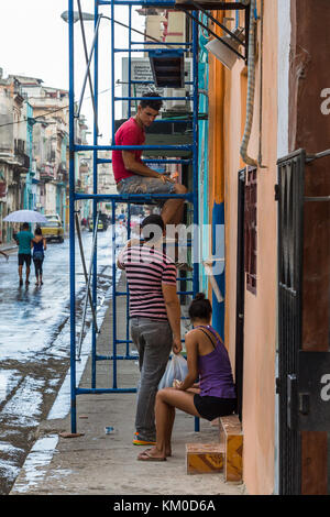 Un homme s'arrête sur un échafaudage mobile unité pour parler à des amis lors d'un travail de décoration à l'extérieur d'une maison à Centro Havana, vu au cours du mois de novembre Banque D'Images