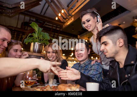 Trois jeunes gens heureux assis et jouer jeu Roche-Papier-Ciseaux Banque D'Images