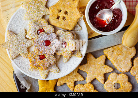 Fait à la maison d'épices et de formes diverses étoiles sablés avec de la confiture de fleurs maison en poudre linzer sur la plaque de cuisson bois rouleau bol wit Banque D'Images