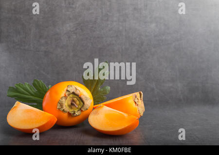 Fruit kaki sur un fond noir en gris Banque D'Images