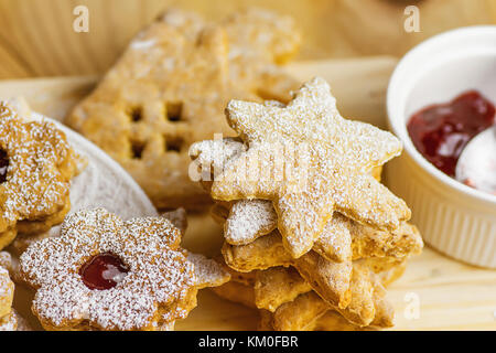 Pile de sablés faits maison et d'épices Biscuits linzer diverses formes étoiles fleur avec de la confiture maison. en poudre. Vue de dessus de table en bois lumière douce ambiance f Banque D'Images