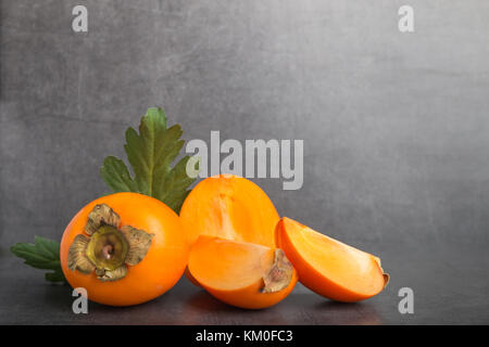 Fruit kaki sur un fond noir en gris Banque D'Images