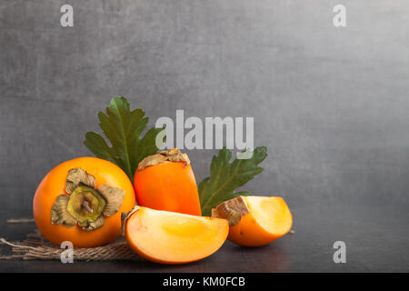 Fruit kaki sur un fond noir en gris Banque D'Images