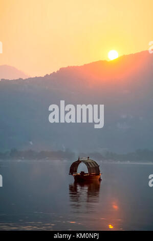 Soleil du matin apparaissant sur les montagnes dans le lac avec fisihing dorénavant nommée unique bateau flottant sur le lac. Banque D'Images