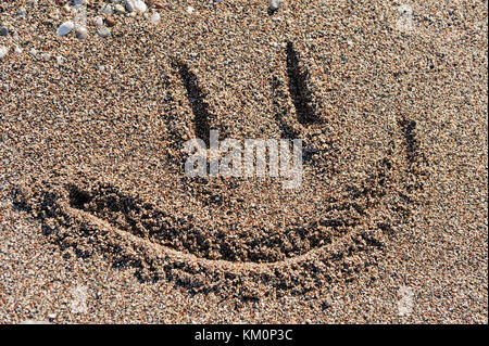 Dessin de smiley sur une plage petite pierre Banque D'Images