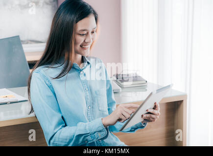 Asian businesswoman utiliser un comprimé à l'conférence en ligne, réunion avec le visage souriant, heureux de la vie de bureau concept,femme qui travaille au bureau d'accueil moderne. Banque D'Images