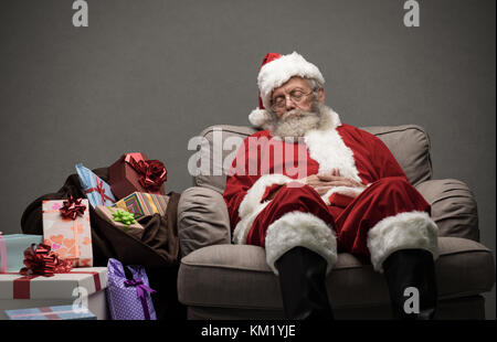 Sleepy santa claus prendre une sieste et reposant sur le fauteuil la veille de Noël Banque D'Images