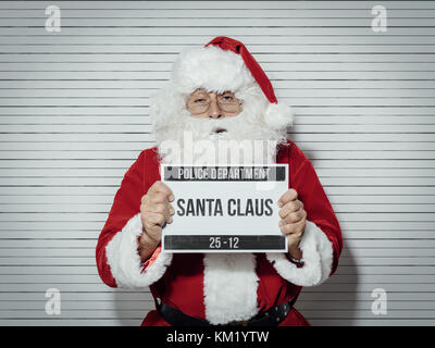 Santa Claus arrêtés la veille de Noël, il est posé pour son mug shot au département de la police et la tenue d'un conseil d'identification Banque D'Images