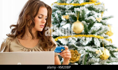 Jeune femme faisant du shopping en ligne near Christmas Tree Banque D'Images