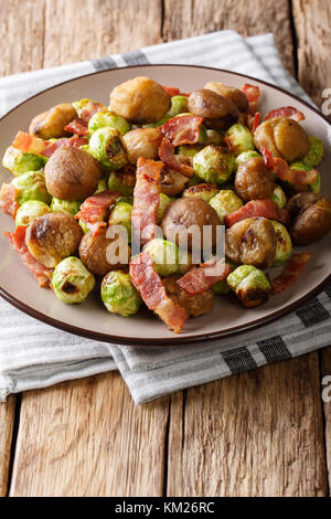 Des châtaignes grillées, salade de choux de Bruxelles et lardons gros plan sur une plaque verticale. Banque D'Images