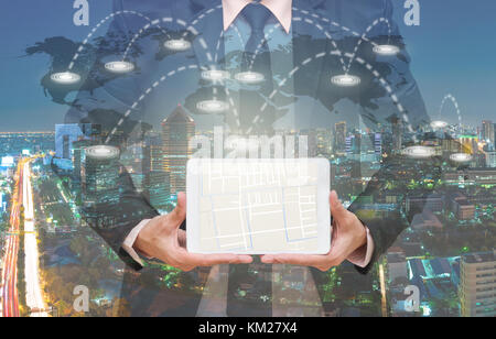 Businessman montrant une partie de la carte navigator sur la surface de la tablette écran sur la ligne de connexion sur la carte du monde avec cityscape, concept de navigation Banque D'Images