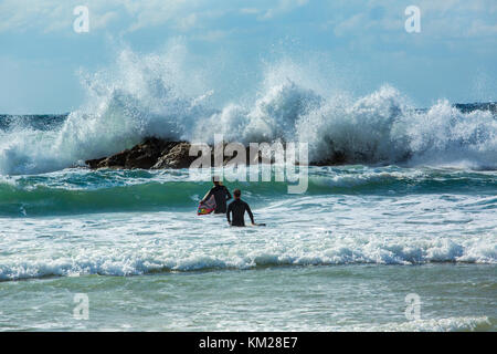 Deux internautes entrant dans la mer avec une planche de surf par un jour de vent à Tel Aviv, Israël Banque D'Images