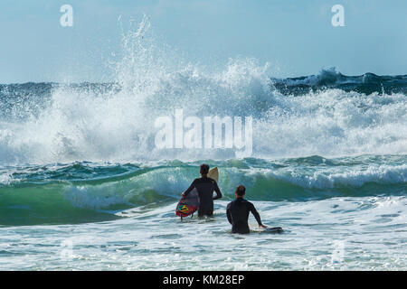 Deux internautes entrant dans la mer avec une planche de surf par un jour de vent à Tel Aviv, Israël Banque D'Images