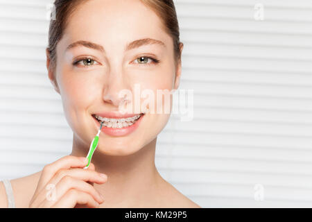 Portrait of happy young woman cleaning ses dents accolades par brosse interdentaire contre l'arrière-plan avec copy-space Banque D'Images