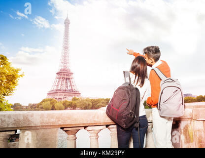 Vue arrière du jeune couple avec des sacs debout à la quai de Seine et dirigée vers la tour Eiffel, marcher le long de Paris, France Banque D'Images