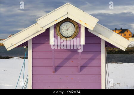 En bois peint blanc et mauve-parement à clin avec stand port horloge des marées sur le mur sous l'avant-toit à pignon toit blanc cottage jaune en arrière-plan Banque D'Images