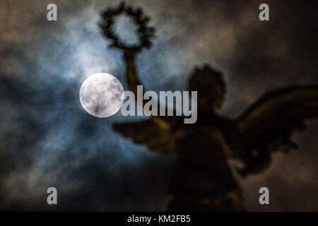 Aberystwyth Wales UK, dimanche 03 décembre 2017 la «Supermoon», et l'apparence très proche et plus lumineuse de la pleine lune, grimpe dans le ciel derrière la couronne tenue dans la main tendue de la sculpture de l'Ange de la paix, au sommet du mémorial de guerre distinctif d'Aberystwyth. Crédit : keith morris/Alamy Live News Banque D'Images