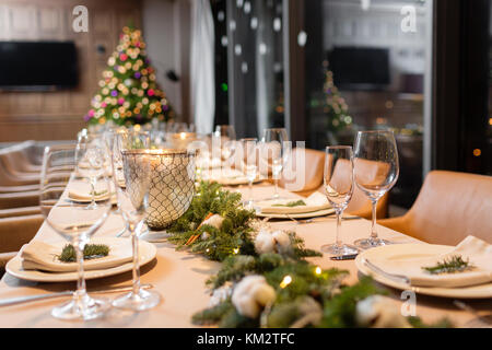 Le dîner de Noël fête. une table de salle à manger décorée avec des verres de champagne et l'arbre de Noël en arrière-plan Banque D'Images