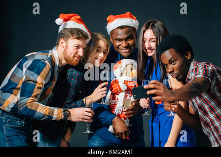 Les filles et les gars à santa hats faisant partie de selfies. Noël, nouvel an concept Banque D'Images