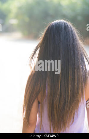 Vue arrière d'une jeune femme aux longs cheveux noirs standing outdoors Banque D'Images