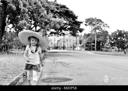 Jeune fille portant un sombrero marche dans une rue de banlieue, Townsville, Queensland, Australie Banque D'Images