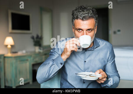 Mature businessman de boire du café dans une chambre d'hôtel. Banque D'Images