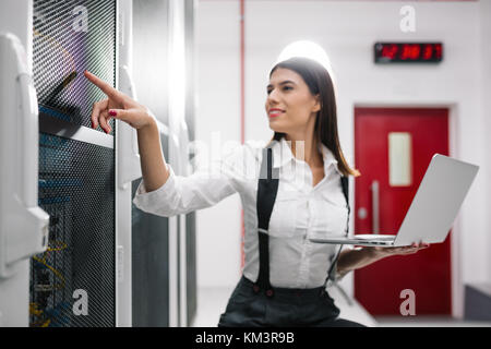 Portrait de technicien travaillant sur ordinateur portable en salle serveur Banque D'Images
