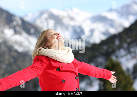 Portrait d'une femme portant un manteau rouge de respirer l'air frais dans la montagne en hiver Banque D'Images