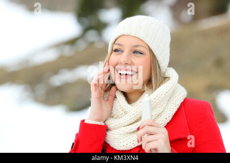 Femme heureuse pour la peau du visage hydratant avec la crème hydratante crème dans une montagne enneigée en hiver Banque D'Images