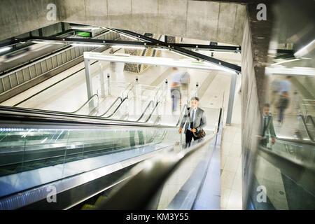 Homme d'affaires sur un escalator sur une station de métro. Banque D'Images