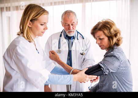 L'examen d'un médecin senior senior woman in office. Banque D'Images
