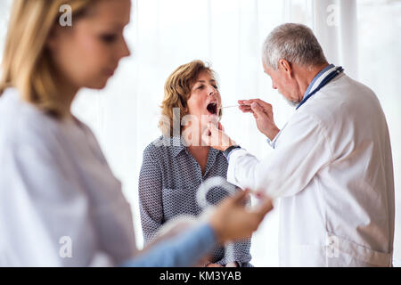 L'examen d'un médecin senior senior woman in office. Banque D'Images