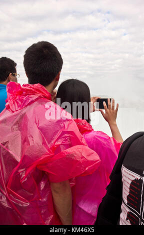 Jeune couple asiatique à Niagara Falls Canada prenant cell phone photos de la Horseshoe Falls. Les touristes. Banque D'Images