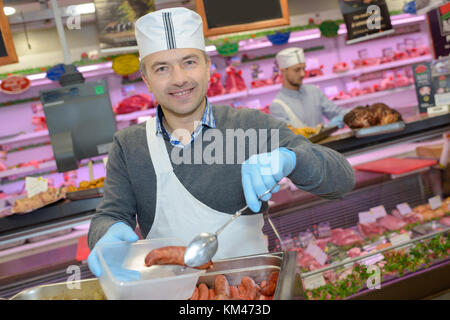 Boucher l'enseignement d'un jeune comment vendre la viande Banque D'Images