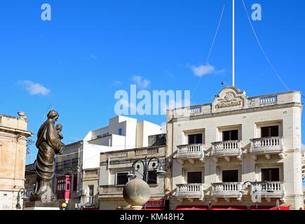 Statue devant le dôme de Mosta avec l'ancien cinéma Paramount à l'arrière des bâtiments autour de la place de la rotonde dans le centre-ville, Mosta, de Malte, de l'Europe. Banque D'Images