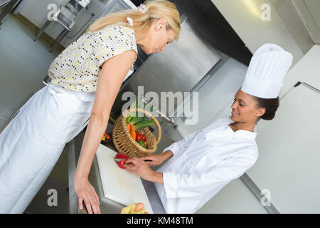 Deux femmes chefs travaillant à côté de l'autre dans la cuisine de l'hôtel Banque D'Images
