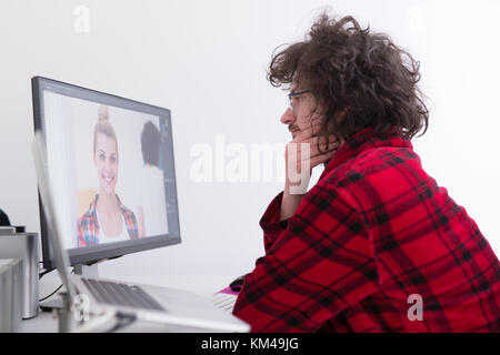 Jeune graphiste à peignoir travaillant au bureau à domicile à l'aide d'ordinateur Banque D'Images
