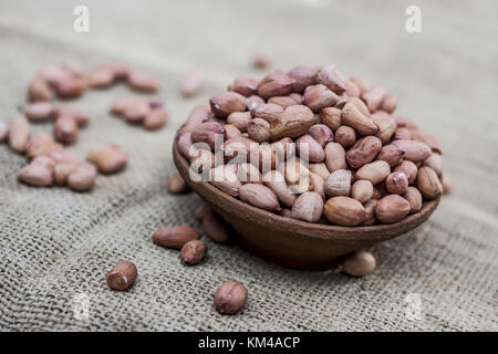 Arachis hypogaea, cru arachides fraîches dans une cuvette d'argile sur fond de jute Banque D'Images