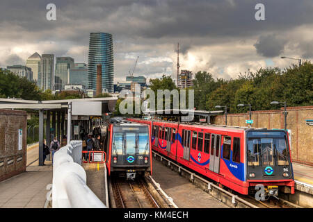 Les passagers montent à bord d'un train léger du Dockland à la station Mudchute DLR avec les tours de Canary Wharf au loin, Londres, Royaume-Uni Banque D'Images